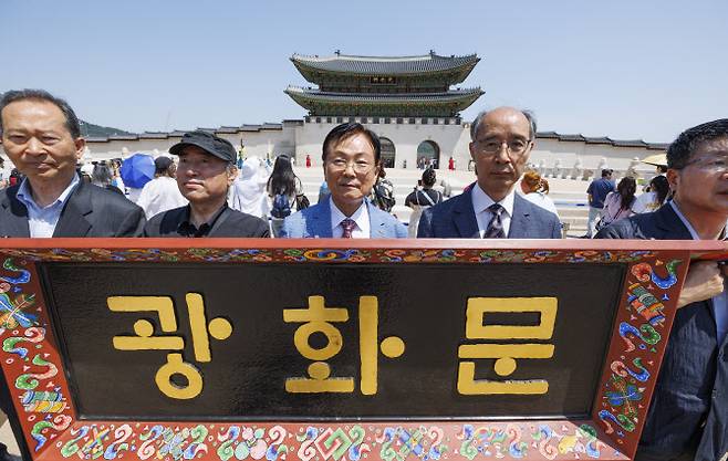 29일 오전 서울 종로구 광화문 광장에서 한글학회와 한글문화단체, 한글을 사랑하는 시민들이 주최한 기자회견 참석자들이 한자로 된 광화문 현판의 한글 교체를 촉구하는 성명서를 낭독한 뒤 한글 모형 현판을 들고 광화문 앞에서 기념 촬영하고 있다(연합뉴스).