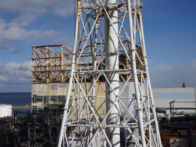 2011년 동일본대지진으로 수소 폭발 사고가 일어난 후쿠시마 제1원전 1호기(뒤에 있는 건물)를 지난해 2월 촬영한 모습. 폭발 사고로 건물 윗부분이 날아가고 철근 등이 구부러지는 등 사고 흔적이 그대로 남아 있다. 연합뉴스 자료사진