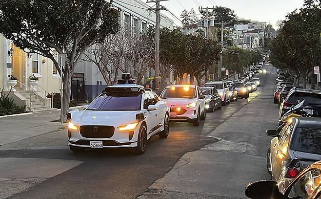 무인 로보택시 승객이 뒷문을 제대로 닫지 않고 가는 바람에 웨이모 차량이 멈춰 섰다. 사람이 와서 조치할 때까지 뒤로 긴 정체가 이어졌다. 2023년 8월 샌프란시스코. 사진 : AP-연합