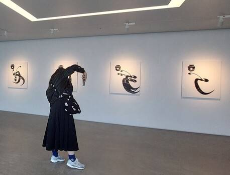 안상수 작가의 개인전이 열리고 있는 오케이엔피부산 전시장. 관객이 그의 한글문자도 작품들을 보며 사진을 찍고있다.