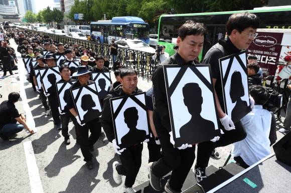 악성민원 희생자 추모 - 지난 4월 29일 오후 서울 태평로에서 전국공무원노조와 대한민국공무원노조 주최로 열린 ‘악성 민원 희생자 추모 공무원노동자대회’에서 참가자들이 영정을 들고 단상에 오르고 있다.  뉴스1