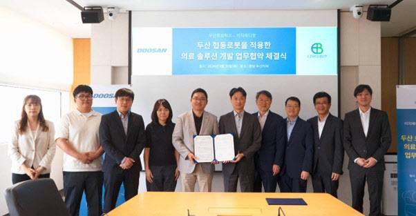 류정훈(왼쪽 다섯번째부터) 두산로보틱스 대표이사와 이윤석 이지메디봇 대표이사, 김병규 한국항공대학교 교수, 정현훈 서울대 산부인과 교수 등 양사 임직원이 협약식에 참석해 기념사진을 찍고 있다. (사진=더블유에스아이)