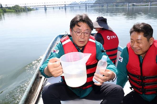 홍태용 경남 김해시장이 배 위에 앉아 낙동강물을 떠서 살펴보고 있다. [사진제공=김해시청]