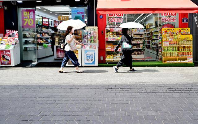 폭염이 한창인 지난해 8월 7일 서울 중구 명동거리에서 '개문(開門) 냉방'을 하고 있는 가게들 앞으로 시민들이 양산을 쓰고 지나가고 있습니다. 한국에너지공단 분석에 따르면 문을 열어놓고 냉방을 할 경우 문을 닫았을 때보다 전력 소비량은 66% 늘고, 전기 요금은 33% 증가합니다. 자원 낭비인 것이죠. 상가 개문 냉방은 최대 300만 원의 과태료가 부과될 수 있지만 실상 단속이 쉽지 않습니다. 최주연 기자