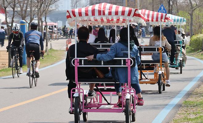 지난 4월7일 주말을 맞아 나들이 나온 시민들이 서울 여의도한강공원에서 4인승 자전거를 타고 있다. 연합뉴스