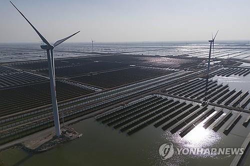 중국 산둥성의 태양광 발전소 주변에서 풍력 터빈이 돌아가는 모습. [AP 연합뉴스 자료사진. 재판매 및 DB 금지]