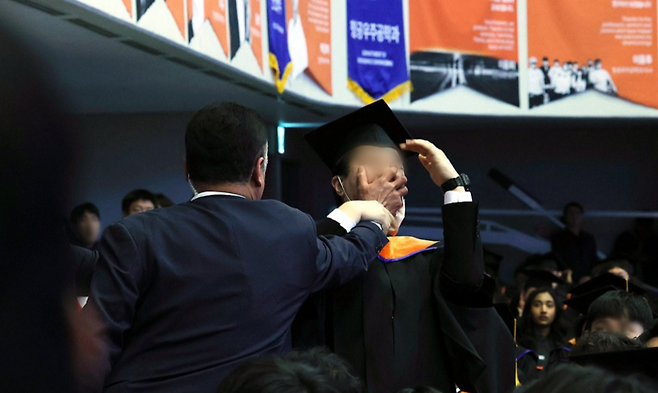 지난 2월 대전 유성구 한국과학기술원(KAIST)에서 열린 학위수여식에서 졸업생 신민기씨가 윤석열 대통령을 향해 연구개발(R&D) 예산 관련 항의를 하던 중 제지를 당하고 있다. [사진 = 연합뉴스]