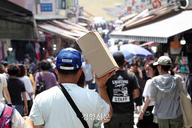 11일 서울 남대문시장에서 한 시민이 종이상자로 햇볕을 가린 채 걸어가고 있다.  정지윤 선임기자