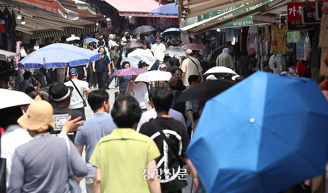 11일 서울 남대문시장에서 시민들이 양산을 쓴 채 로 햇볕을 가린 채 걸어가고 있다. 정지윤 선임기자