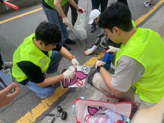 골프존뉴딘그룹 임직원들이 빗물받이 쓰레기 무단투기 예방을 위한 고래 모양 스티커를 부착하고 있다.