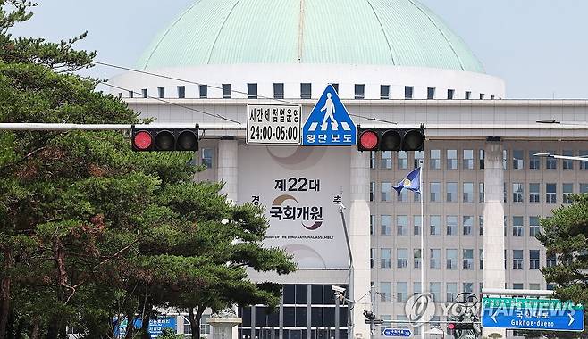 '양보 없는 대치' 지속되는 국회 (서울=연합뉴스) 김주형 기자 = 여야가 상임위원회를 배분하는 원구성 문제를 두고 강대강 대치를 이어가고 있는 9일 서울 여의도 국회의사당 앞 교통신호등 너머로 22대 국회개원 축하 현수막이 보인다. 2024.6.9 kjhpress@yna.co.kr