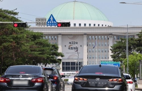 여야가 상임위원회를 배분하는 원 구성 문제를 두고 강 대 강 대치를 이어가는 가운데 국회의사당 앞 교통신호등 너머로 22대 국회 개원 축하 현수막이 보인다.  [연합뉴스]