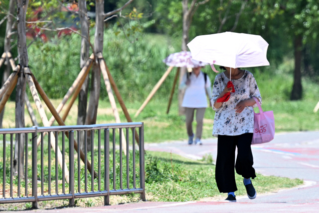 ▲ 자외선과 오존 농도가 나쁨을 보인 지난 12일 춘천 공지천 산책로에서 시민들이 양산을 쓰고 걷고 있다. [강원도민일보 자료사진]