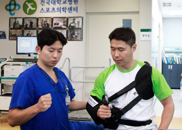 정석원 건국대병원 정형외과 교수(왼쪽)가 어깨 회전근개 봉합 수술 후 보조기를 낀 상태에서 악력 운동을 하는 방법에 대해 설명하고 있다.