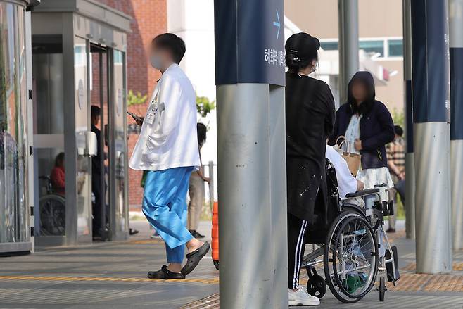 19일 오후 서울 종로구 서울대병원을 찾은 환자와 보호자가 차량을 기다리는 가운데 의료 관계자가 이동하고 있다. 연합뉴스