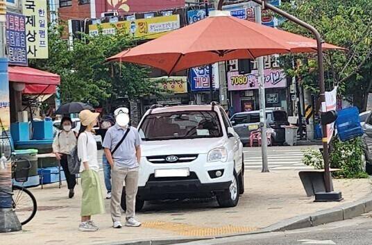지난해 6월 횡단보도 신호를 기다리는 보행자를 위해 설치된 그늘막 아래 주차된 차들이 전국 곳곳에서 포착돼 공분을 샀다. 온라인 커뮤니티 갈무리