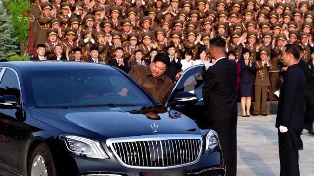 김정은 위원장이 5월 22일 노동당 중앙간부학교 건설에 참여한 군인·설계자들과 기념 공연을 한 예술인들과 기념촬영을 마치고 메르세데스-벤츠 운전석에 탑승하고 있다. 조선중앙TV 화면
