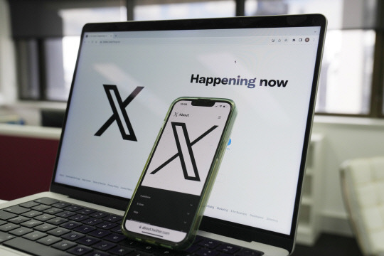 FILE - The opening page of X is displayed on a computer and phone, Oct. 16, 2023, in Sydney. The social media platform X says it will now allow people to show consensual adult content, as long as it is clearly labeled as such. The move formalizes a policy already in place when the platform was known as Twitter, before billionaire Elon Musk purchased it in 2022. (AP Photo/Rick Rycroft, File) FILE PHOTO