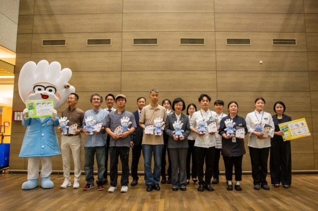 27일 아워홈 한식소담길 인천공항 제1터미널점에서 진행된 위생등급제 ‘매우 우수’ 획득 기념 현판식에서 오유경 식약처장과 직원들이 기념 촬영을 하고 있다. [사진 = 아워홈 제공]