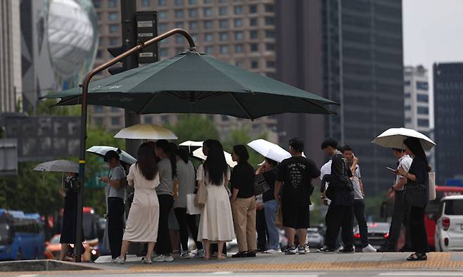 무더위가 계속되는 27일 서울 광화문광장에서 시민들이 그늘 아래서 보행 신호를 기다리고 있다. 연합뉴스