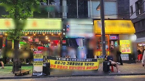 28일 오후 8시쯤 서울 종로구 돈화문로11길 포장마차 거리에 "종로구는 건물 통행로를 가로막는, 불법을 허용하는 비상식행정을 철회하라"는 내용의 현수막이 걸렸다. 김서원 기자