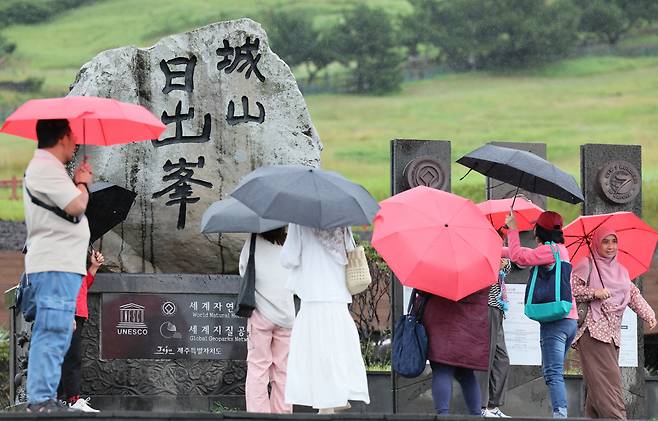 제주도에 호우주의보가 내려진 27일 오전 우산을 쓴 외국인 관광객들이 서귀포시 성산읍 성산일출봉을 탐방하고 있다. [연합]