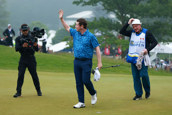 Robert MacIntyre waves in celebration of his win on the 18th green alongside his caddie and father Dougie MacIntyre during the final round of the RBC Canadian Open at Hamilton Golf & Country Club on June 2 in Hamilton, Canada. [GETTY IMAGES]