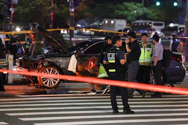 1일 밤 대형 교통사고가 발생한 서울 시청역 인근 교차로에서 경찰이 완전히 파괴된 차량 한 대 주변을 통제하고 있다. [사진 출처 = 연합뉴스]
