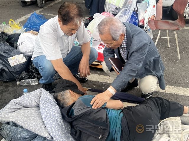 김 목사가 무료 급식 봉사 후 인근 거리에서 노숙 중인 이의 팔에 손을 얹고 기도해주고 있다. 임보혁 기자