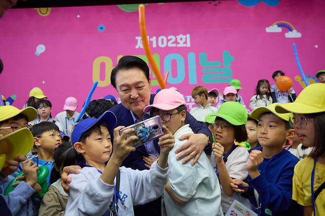 윤석열 대통령이 지난 5월5일 청와대 연무관에서 열린 어린이날 초청 행사에 참석해 어린이들과 셀카를 찍고 있다. [대통령실 제공]