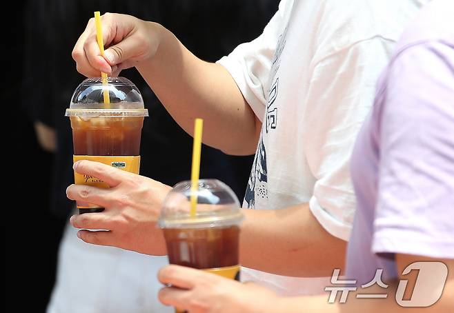 서울 시내에 위치한 커피 매장 앞에서 시민들이 커피를 들고 이동하고 있다. 2024.7.1/뉴스1 ⓒ News1 임세영 기자