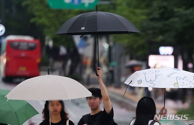 [서울=뉴시스] 김명년 기자 = 비가 내린 7일 오후 서울 종로구 광화문광장에서 한 시민이 우산을 다른 사람과 부딪히지 않게 높게 들고 횡단보도를 건너고 있다. 2024.07.07. kmn@newsis.com