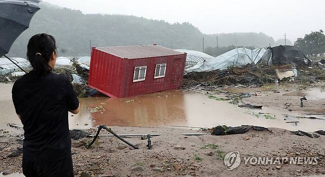 폭우 피해 현장 (완주=연합뉴스) 최영수 기자 = 한 주민이 10일 폭우로 전북 완주군 운주면 엄목마을 앞 컨테이너와 비닐하우스 피해 현장을 걱정스럽게 바라보고 있다.  2024.7.10 kan@yna.co.kr