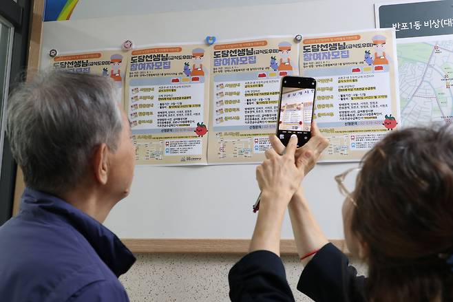 정년이 넘은 나이에도 은퇴하지 못하고 직업 전선에 나서는 60대 이상 연령층이 늘고 있다. 지난해 10월 서울의 한 주민센터 민원실 입구에서 장년층 구직자들이 급식 도우미 모집 포스터를 보고 있다. /전기병 기자