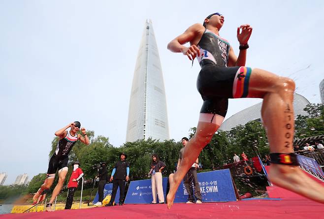 14일 오전 서울 송파구 롯데월드타워 일대에서 열린 '2024 롯데 아쿠아슬론'에 출전한 참가자들이 석촌호수에서 수영을 마치고 수직마라톤을 향해 달리고 있다. /뉴스1