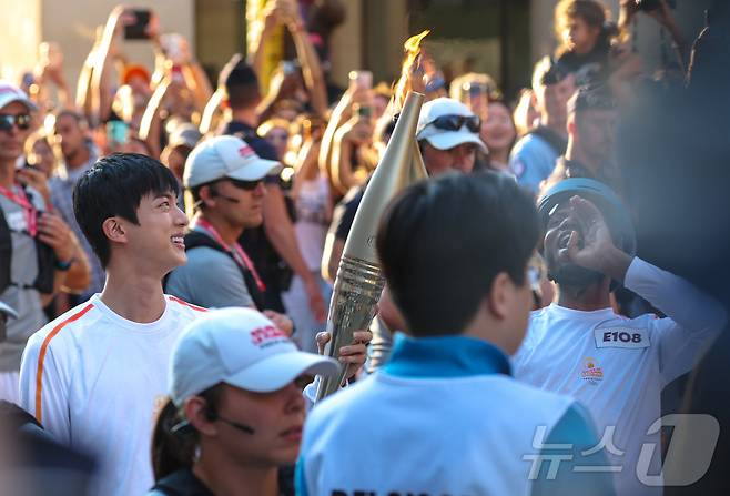 2024 파리 올림픽 성화 봉송 주자로 나선 아이돌 그룹 방탄소년단(BTS)의 맏형 진이 프랑스 혁명기념일인 14일(현지시간) 프랑스 파리 루브르 박물관 인근 도로에서 아미두 피소루에게 성화를 인계 받고 있다. 2024.7.15/뉴스1 ⓒ News1 이준성 기자