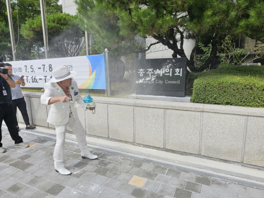 오천도 애국국민운동대연합 대표가 16일 충주시의원 아들의 성폭력 사건을 비판하면서 시의회 표지석에 밀가루 세례를 퍼붓고 있다. 사진=진광호 기자