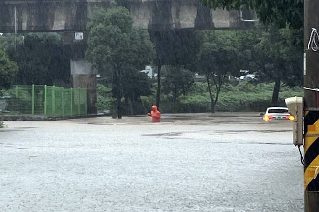 전남 동부권에 호우경보가 내려진 16일 오후 여수시 중흥동 중흥천 인근 도로가 침수돼 소방대원이 안전조치를 하고 있다. 연합뉴스