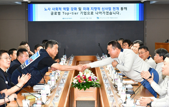 Hyundai Motor President and co-CEO Lee Dong-seock, right, and labor union head Moon Yong-moon shake hands at the signing ceremony for the improved compensation package at the company’s Ulsan plant on Monday. [HYUNDAI MOTOR]