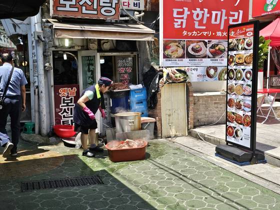An employee at a restaurant serving bosintang, a hot stew featuring boiled dog meat, boils the meat outside the establishment. [JOONGANG ILBO]