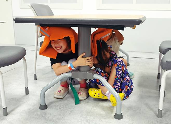 초등학생들이 자연재난안전체험실에서 지진으로 갑자기 교실 바닥이 흔들리자 급히 책상 밑으로 대피했다.