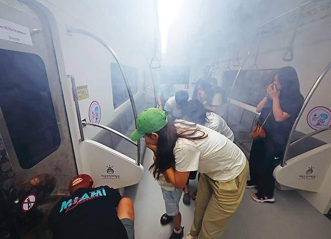 지하철안전체험실에서 한 참가자가 불이 난 지하철 문을 열고 탈출하기 위해 비상 레버를 젖히고 있다.