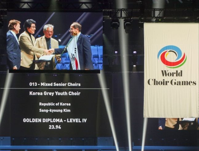 19일 '2024 세계합창경연대회'(World Choir Games) 시상식에서 남자의 자격 청춘합창단 윤학수 단장과 김상경 지휘자가 시니어 부문 대상을 수상하고 있다. [사진제공 = 남자의 자격 청춘합창단]