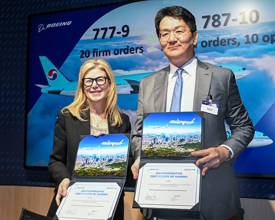 Stephanie Pope, left, CEO of Boeing Commercial Airplanes and Walter Cho, Chairman of Korean Air, take a photo after signing an agreement to purchase 50 Boeing aircraft at the Farnborough International Airshow on Monday. [KOREAN AIR]