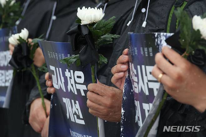 [서울=뉴시스] 조성봉 기자 = 지난 18일 오후 서울 여의도 국회 본청 계단에서 열린 '공교육 정상화 특별법 제정 촉구, 순직교사 1주기 전교조 추모기자회견'에서 참석자들이 국화와 손피켓을 들고  있다. 2024.07.23 suncho21@newsis.com