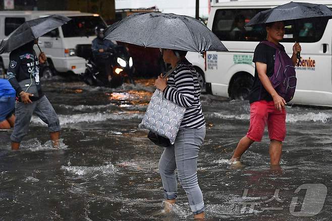 필리핀 마닐라 시민들이 23일 3호 태풍 '개미'가 몰고온 폭우로 물이 차오른 마닐라 거리를 걷고 있다. 2024.07.23 ⓒ AFP=뉴스1 ⓒ News1 권진영 기자