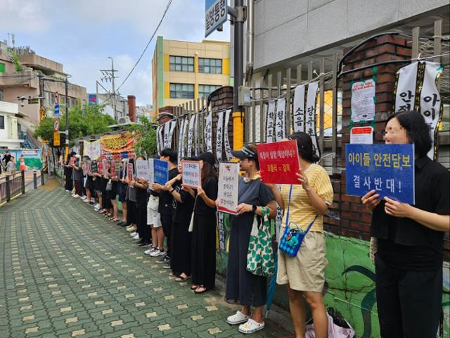 24일 서울 관악구 당곡초등학교 앞에서 학부모들이 손팻말을 든 채 시위하고 있다. 최현빈 기자