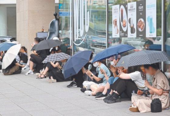 25일 서울 강남구 티몬 본사 앞에서 환불을 원하는 피해자들이 우산을 쓰고 사측을 기다리고 있다. 연합뉴스