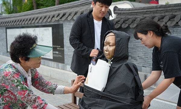 충남 예산의 캠페인 참여자들이 비를 맞는 소녀상에 우의를 입히고 있다. 경기도 제공