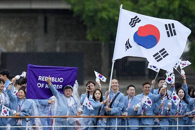 김서영과 우상혁(가운데)이 27일 열린 파리올림픽 개회식에서 태극기를 들고 퍼레이드에 나서고 있다. AP연합뉴스